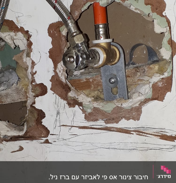צינור מתכת וברז בתוך קיר פתוח